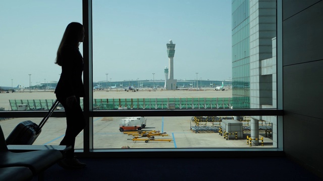 一名女乘客靠在航站楼窗户上的剪影，慢镜头视频素材