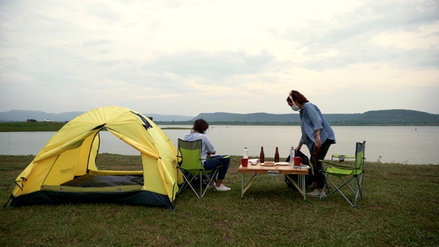 一个场景，两个亚洲女子背包客正在享受日落在湖边在暑假。他们是快乐的，有乐趣的假期，放松的时刻。青少年自然户外日常生活的概念视频素材