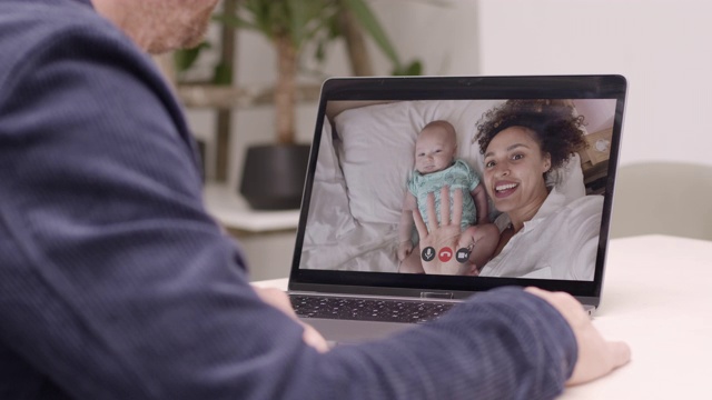 母亲和她的新生儿在床上用厨房桌子上的笔记本电脑与家人视频通话视频素材