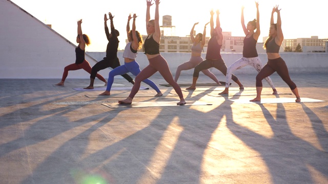 MS TU瑜伽班移动武士姿势在日落屋顶锻炼会议视频素材