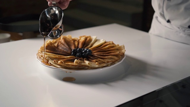 餐厅厨房专业厨师为煎饼倒蜂蜜或枫糖浆。视频素材