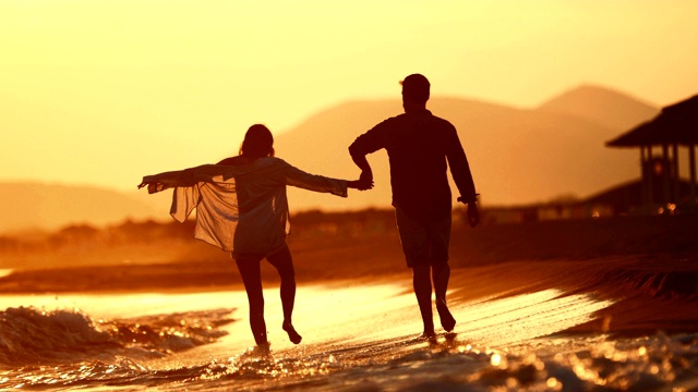 年轻夫妇在海滩上享受浪漫的日落。视频素材