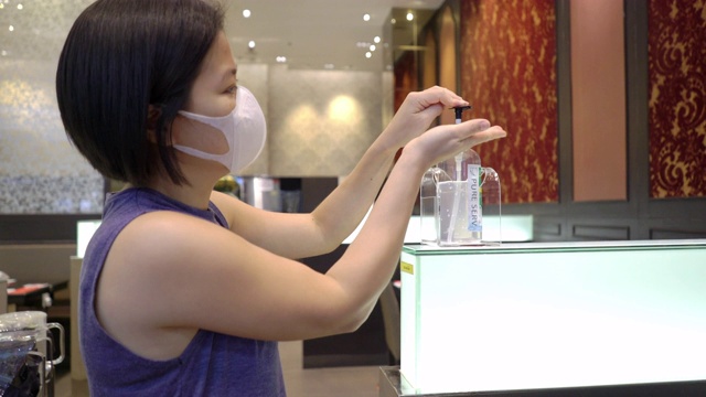 与家人在餐厅吃完食物后，戴着保护面罩用酒精洗手液洗手的亚洲妇女视频下载