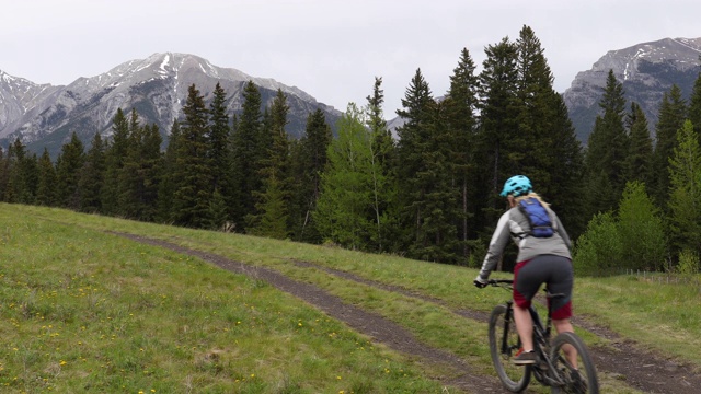 山地自行车夫妇穿越草地轨道在阴天视频素材