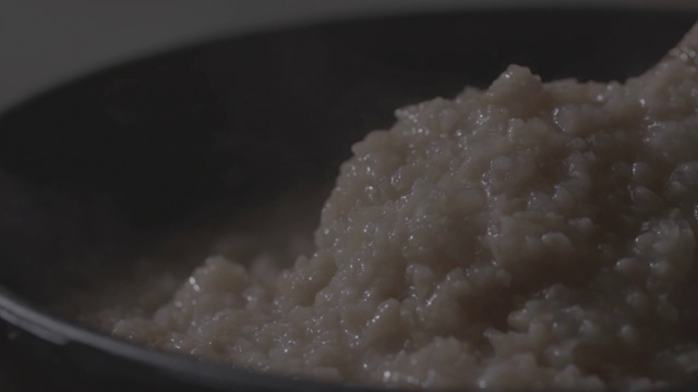 用勺子搅动烤焦的米粥视频素材