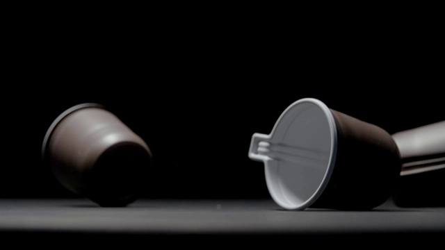 热饮塑料杯落在黑色背景慢动作视频上。视频下载