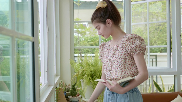 亚洲女人在室内放松的场景，早晨的小花园，绿色的概念的现代住宅视频下载