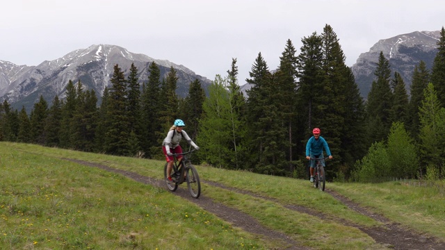 山地自行车夫妇穿越草地轨道在阴天视频素材