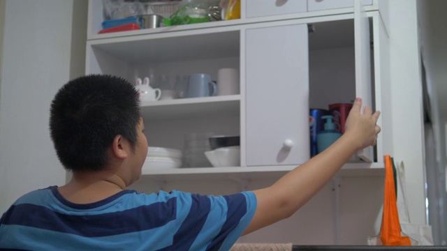 亚洲十来岁的男孩拿着白色盘子，把盘子放在架子上。视频素材