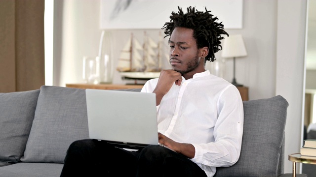 非洲人在家用笔记本电脑思考和工作视频素材
