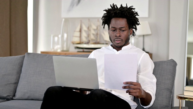 非洲人在家里工作的文件和笔记本电脑视频素材