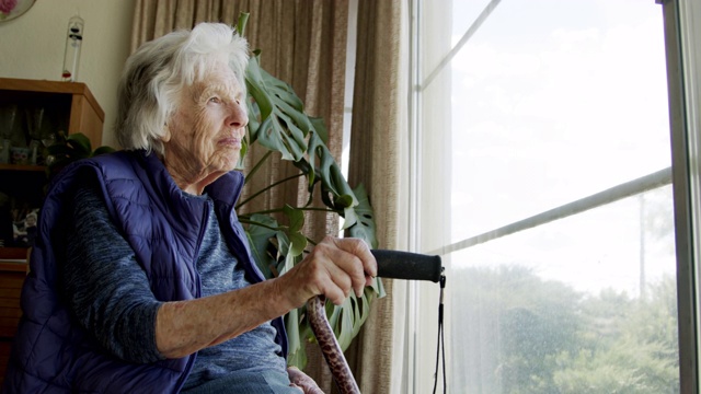 一个快乐的，舒适的老年白人妇女在夏天看窗外的广角拍摄视频素材
