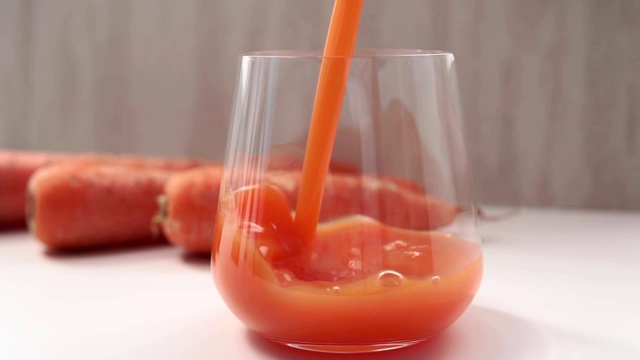 在厨房里斟满新鲜胡萝卜汁。健康饮食的概念视频素材