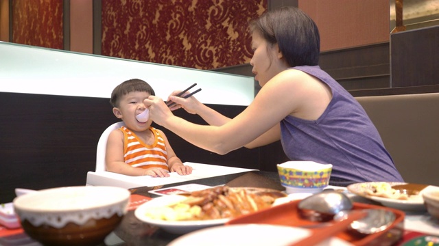 快乐的亚洲母亲和儿子一起在餐厅吃午饭。视频素材