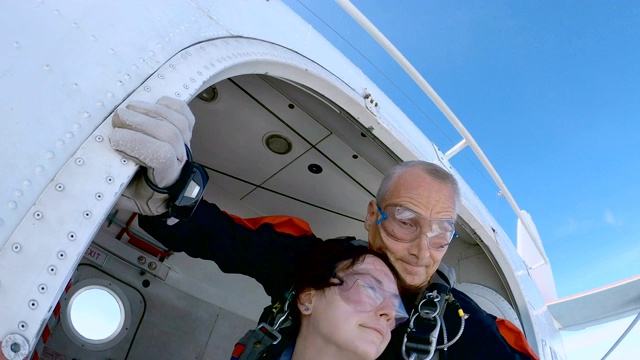 教练和一名女子正带着降落伞跳出飞机。视频下载