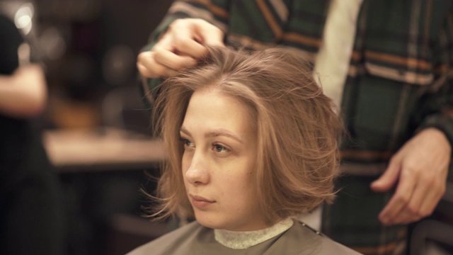 美发师为女性顾客提供理发后的手工造型视频下载