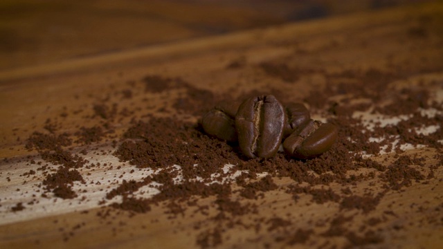 4k慢镜头的咖啡豆和咖啡粉在木桌上旋转视频下载