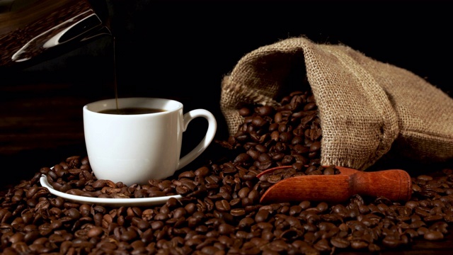 用咖啡粗麻袋和咖啡豆将新鲜咖啡倒入白咖啡杯中视频下载