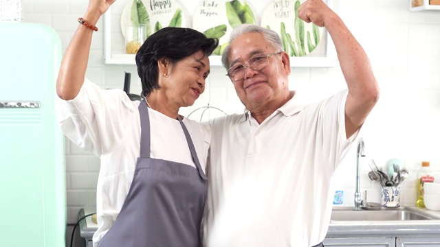 年长的亚洲夫妇在厨房做饭。70多岁的老人和女人一起在厨房柜台上准备食材视频素材