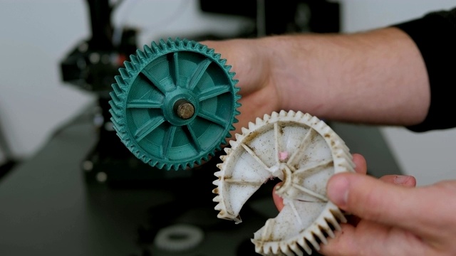 一名男性工程师的特写展示了用3D打印机打印的塑料模型。视频素材