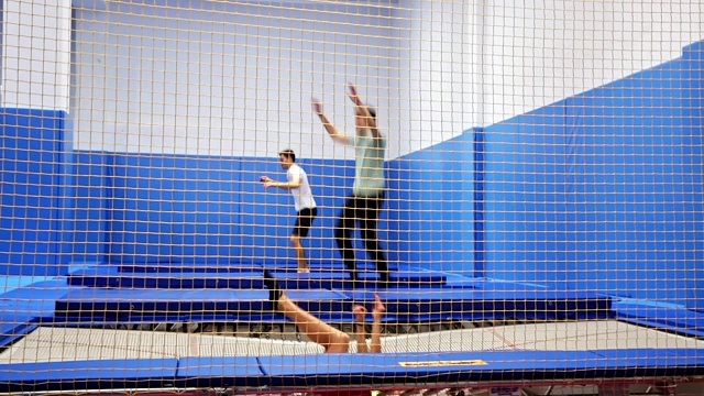 在现代健身中心，女性和男性在蹦床上蹦蹦跳跳视频下载