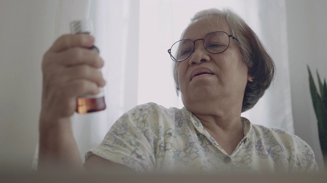 一个亚洲女人拿着药瓶，在客厅用笔记本电脑聊天。视频下载