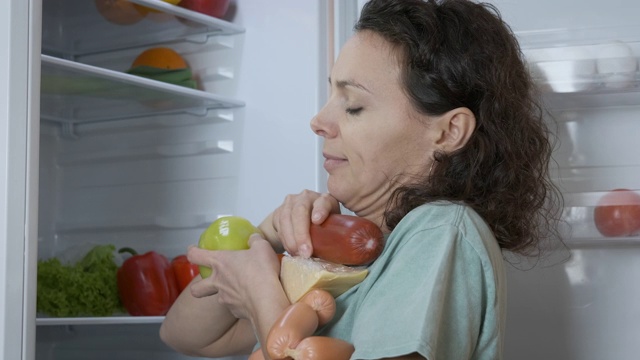 一个女人从冰箱里拿食物。视频下载