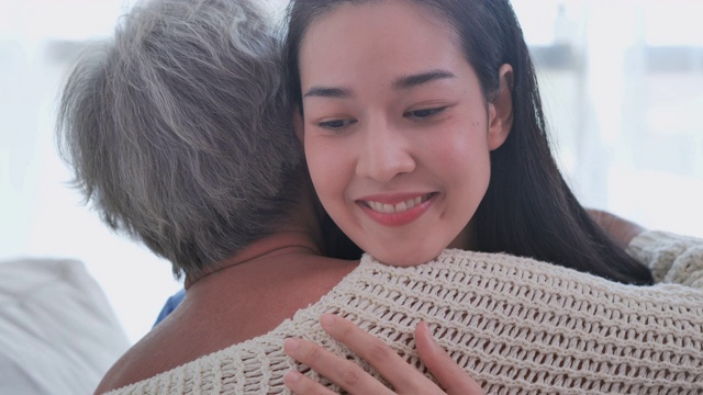 亚洲老年妇女听亚洲年轻女护士医生在咨询和拥抱她的年长女性病人在家里。在家里照顾者视频下载