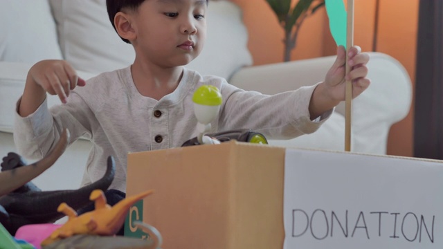 4岁的快乐亚洲小男孩把玩具装进了家里的捐赠箱。教/学捐款的概念视频素材