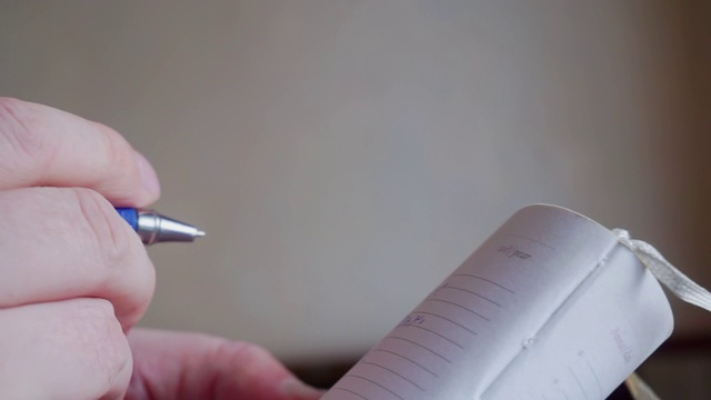 一个男性用铅笔在笔记本上写字的手的特写视频素材