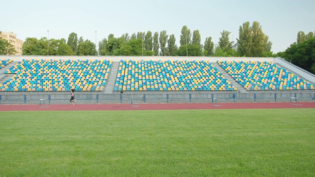 白种女运动员在体育场内练习跨栏，慢镜头。体育场内田径运动训练视频下载