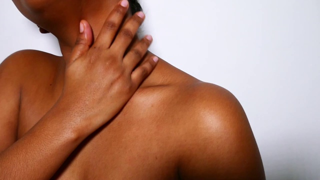 一位年轻美丽的非裔美国女性正在涂抹身体霜。美容护肤常规。视频下载