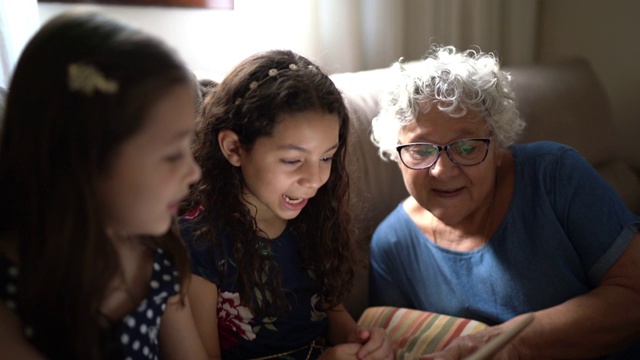 祖母和孙女正在用家里的平板电脑进行视频通话视频素材
