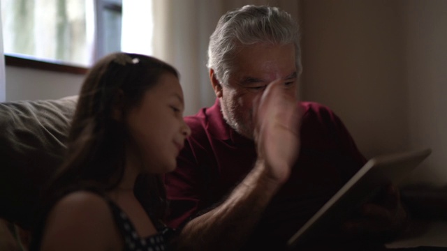 祖父和孙女正在用家里的平板电脑进行视频通话视频素材