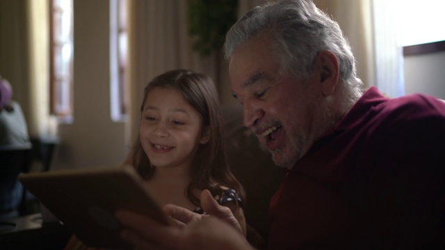 祖父和孙女正在用家里的平板电脑进行视频通话视频素材