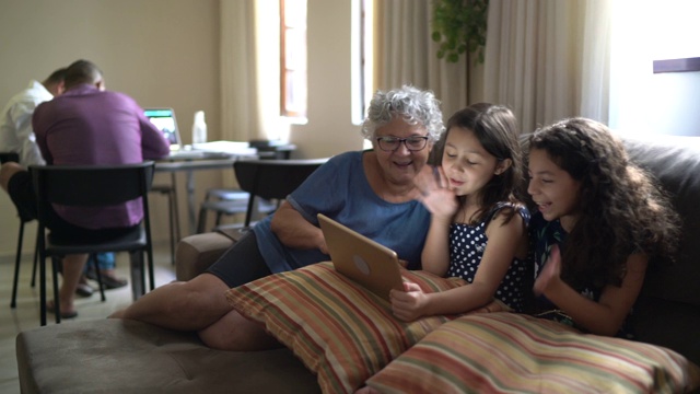 祖母和孙女正在用家里的平板电脑进行视频通话视频素材