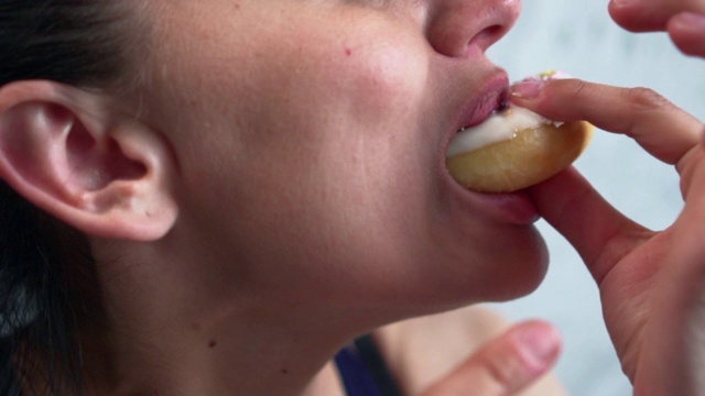女人在吃甜甜圈，特写。视频素材
