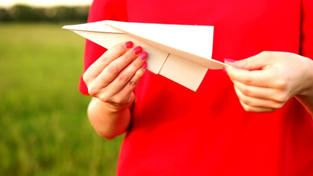 女性手持纸飞机。旅游，玩具，手工，童年，旅游概念。视频素材