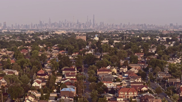 鸟瞰图的比彻斯特住宅区在皇后区与曼哈顿在日出时的远景背景。无人机视频片段与向前摄像机运动视频素材