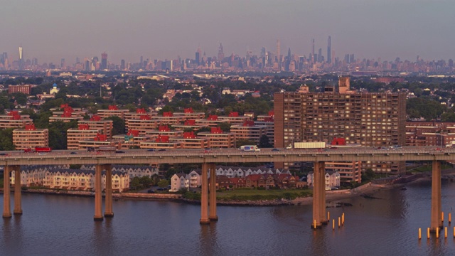 鸟瞰图的比彻斯特住宅区在皇后区与曼哈顿在Throgs颈桥在日出的遥远的背景。无人机视频镜头与全景相机运动视频素材