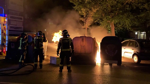 西班牙马德里，不明身份的消防员正在扑灭车辆旁边集装箱里的大火。视频下载