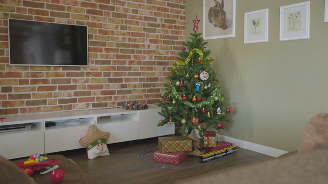 装饰灯的圣诞树。地板上有礼品盒和玩具蒸汽机。视频下载