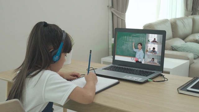 亚洲女学生视频会议电子学习与老师和同学在电脑上在家里的客厅。在家教育和远程学习，在线，教育和互联网。视频下载