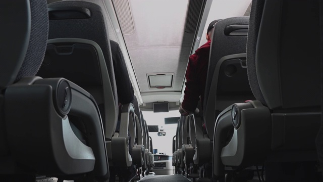 公共汽车上的男性乘客互相交谈调整座位和查看手机。视频下载