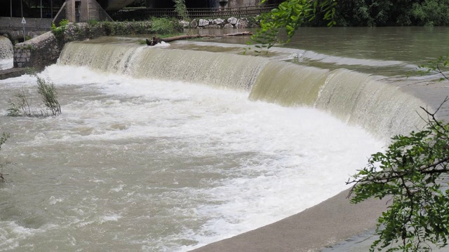 河水从屏障往下流。人们正在修建堤坝，通过控制河流的流速来减少风暴期间的侵蚀。暴雨后塞里奥河被淹视频素材