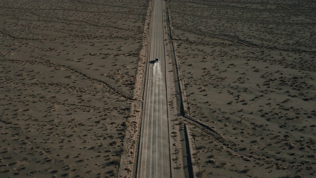 高角度无人机拍摄，在美国内华达州一条尘土飞扬的土路上，跟随在一辆卡车后面视频素材