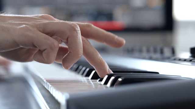 录音棚里的年轻人。右手在钢琴键盘上弹奏的手的特写。学习如何在电子合成器上演奏。学生。视频下载