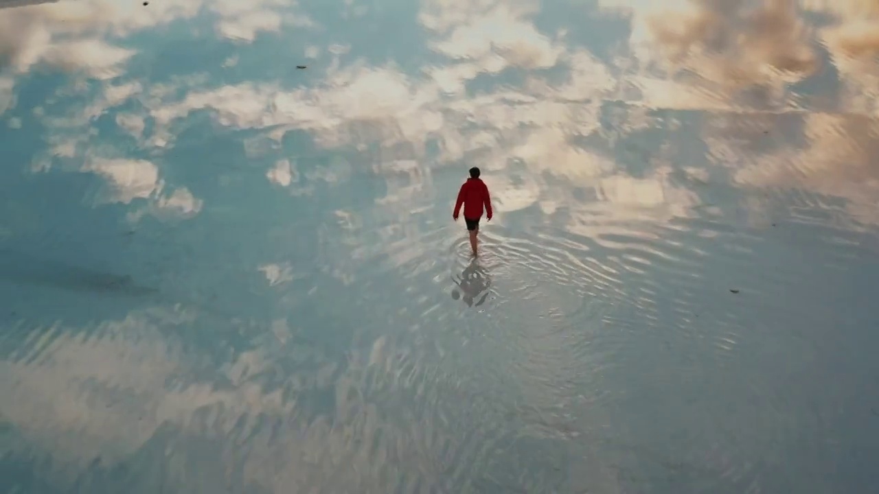 空中平移拍摄，显示了一个成年人在周围行走和云反射在泛滥的博纳维尔盐滩，美国犹他州视频下载