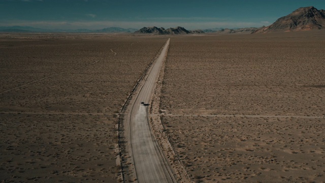 美国内华达州一条干燥偏僻的土路上，一架高角度无人机飞向一辆正在拐弯的卡车视频素材