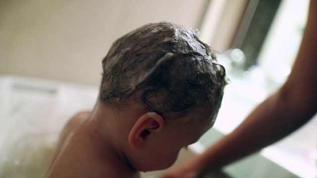 家长在浴缸内给婴儿洗澡，清洗婴儿的例行公事视频素材